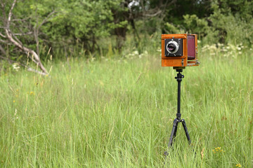 Vintage wooden large format film camera on a sunny meadow with green grass. The old studio camera...