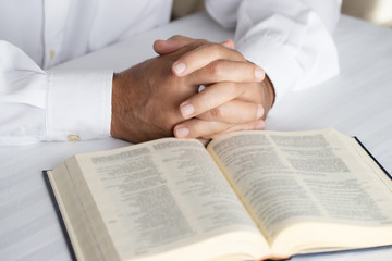 Fototapeta premium Close of hands in player on open Holy Bible. Man praying background.