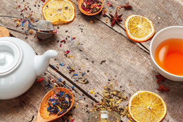 cups of healthy herbal tea with cinnamon, dried rose and camomile flowers in spoons over wooden...