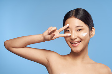 young woman applying cream on her face