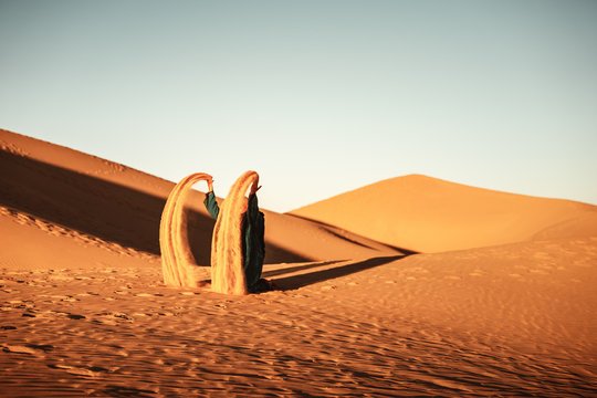 Beduinin wirft Sand in die Luft an einer D&uuml;ne in der W&uuml;ste Sahara in Marokko