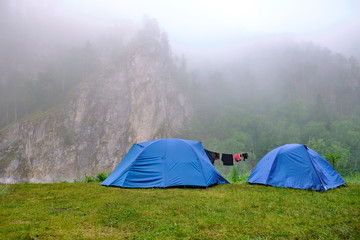 Tents stand in the outdoors mountains, morning mist and fog
