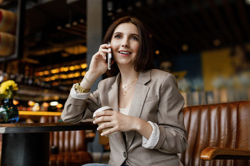 Portrait of young  woman at cafe drinking coffee and using mobile phone