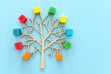 Business image of wooden tree with colorful cubes over blue table, human resources and management...