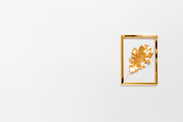 Autumn composition. Golden frame with a gold spray painted natural leaf on white background. Flat lay, top view, copy space.