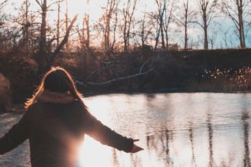 Woman in front of a river with open arms in a gesture of faith, hope or rebirth