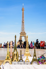 Fototapeta na wymiar The Eiffel tower in Paris, France, pictured with miniature Eiffel towers in the foreground, sold on the Trocadero esplanade by street vendors.