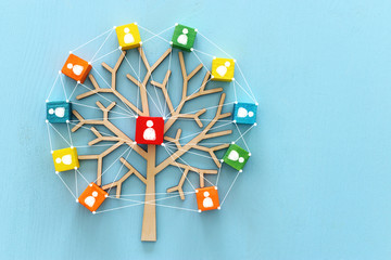 Business image of wooden tree with people icons over blue table, human resources and management...