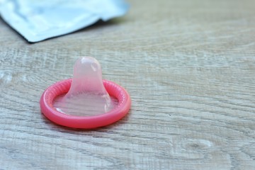 Pink condoms on a wooden table...