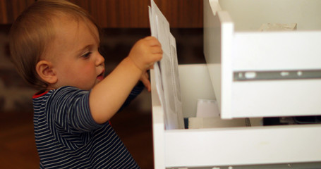 Side view of curious baby boy exploring open drawers