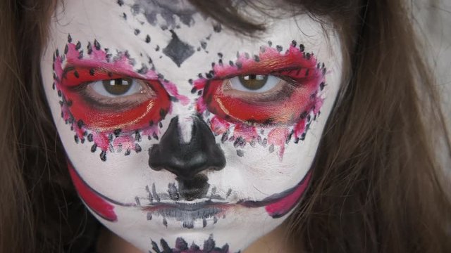 Scary makeup for Halloween. Little girl with skeleton makeup on her face for Halloween. Halloween child.