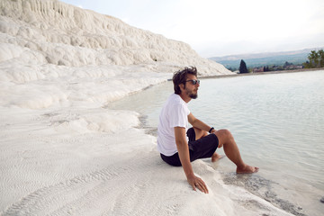 Fototapeta na wymiar man with a beard in a white t-shirt and shorts sitting on a white mountain