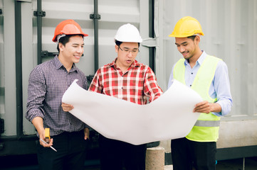 engineer and foreman team looking in blueprint for checking construction progress in construction...