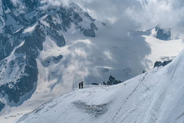Naklejka premium Alpinist returning back to Aiguille Du Midi from Mont-Blanc with vast mountain background in Chamonix, France