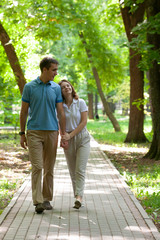 Fototapeta premium Couple walking hand in hand in a park - Romantic date outdoors