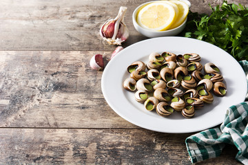 Escargots de Bourgogne on wooden table. Copyspace