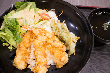 Tempura don, deep fried shrimp with rice and salad Japanese style on black bowl