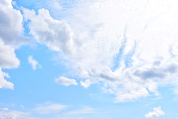 Fototapeta premium Beautiful blue sky with cumulus, selective focus. Blue sky background with fluffy white clouds and sunlight on backdrop. Idyllic wallpaper with cloudy sky and space for text. Cloudscape 