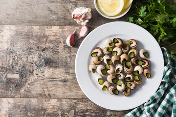 Escargots de Bourgogne on wooden table. Top view. Copyspace