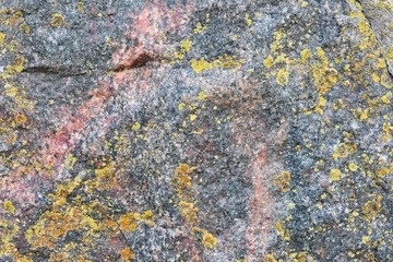 Natural stone background with textured surface and green moss. Pattern mineral with rough structure and yellow lichen. Aging colorful mountain backdrop. Natural stone surface with empty space for text