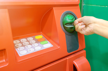 Hand of female insert debit card into automated teller machine (ATM)