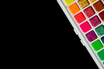 Close up, flat lay. A palette of multicolored watercolor. Isolated on black background. Copy space.