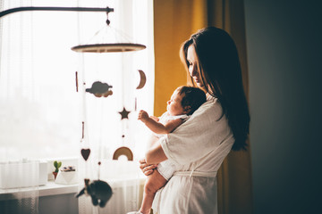 Young mother puts her baby to sleep while she cries. Concept photo parenthood and motherhood.