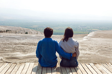 couple man and woman sit back on a wooden floor in the street in Pamukkale