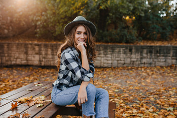 Spectacular brown-haired girl in casual clothes relaxing in park in good autumn weather. Refined...