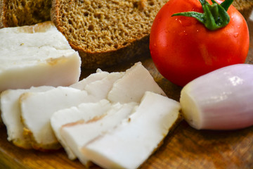Freshly baked bread on a wooden cutting board with bacon, tomatoes and onions