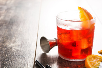 Negroni cocktail with piece of orange in glass on wooden table.. Copyspace