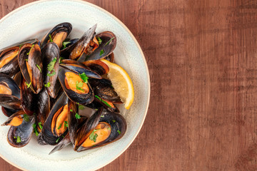 Marinara mussels, moules mariniere, close-up overhead shot on a dark rustic wooden background with copy space