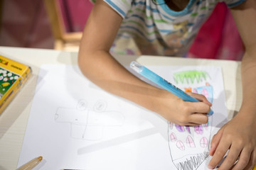 Child writing drawing coloring on paper using crayon