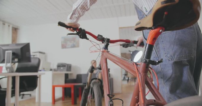 Close up of man who carries bicycle in modern office