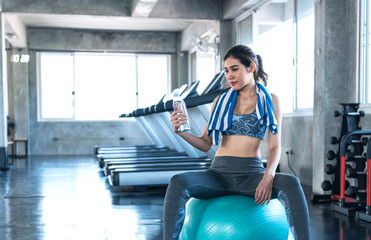 asian women thirsty drinking water after exercise in fitness gym. healthy lifestyle.