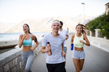 Happy fit people running and jogging together in summer sunny nature