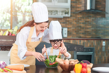 Mom and his little daughter cooking bolognese sauce for salad in the kitchen, there is steam escaping from the pan on cooking plate