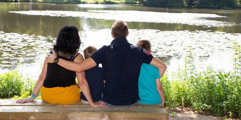Family mother father and brothers children boys sitting on lake wood bench in web banner template header