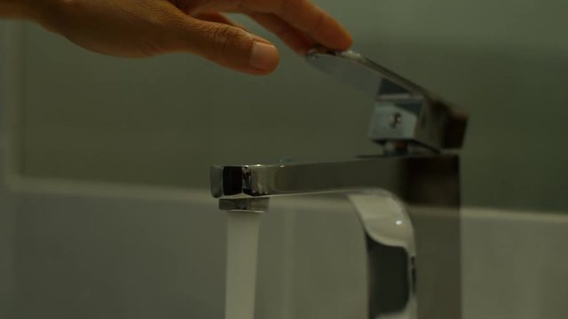 Woman washing her hands by water from faucet.