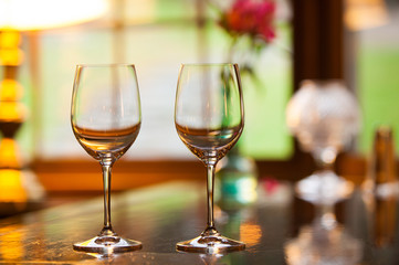Two empty wine glasses on a bar.