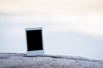 Blank instant photo frame on wood at the beach.