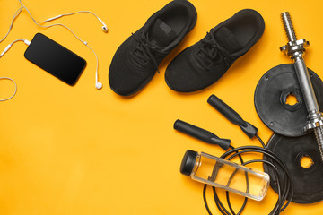 Close-up studio shot of a gym accessories on a yellow background. Top view, flat lay.