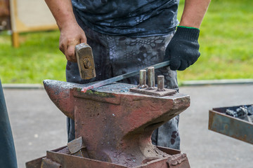 blacksmith crushes the red-hot metal workpiece