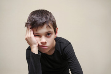 Portrait of the tired boy of the European appearance on a light background. 