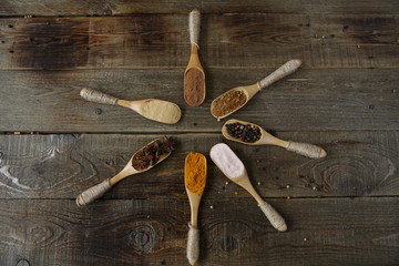 traditional spices: turmeric, ginger, cinnamon, nutmeg, pepper, pink salt, anise in wooden spoons on a wooden background. With copy space for text or image. Flat lay. Top  view. Spices pattern.