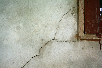 the small cracked on grey wall  near wooden  window in countryside of Thailand