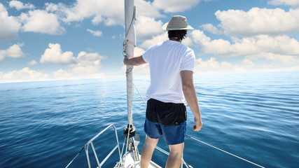 Man standing at the bow of a ship. Yachting, vacation and freedom concept.