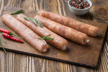 Raw sausage with hot  spices on a dark wooden background
