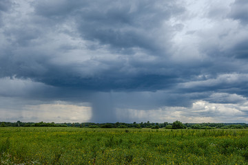 Fototapeta na wymiar storm rain clouds forming over the countryside fields in green summer