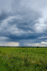 storm rain clouds forming over the countryside fields in green summer